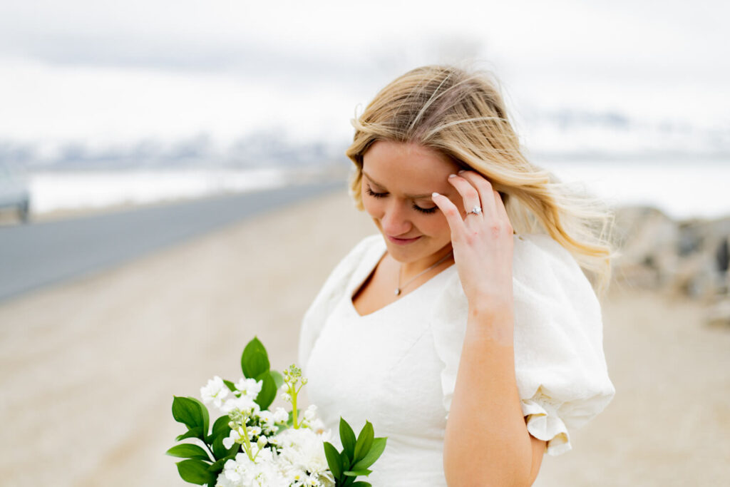 Bride fixing her hair while looking down at her bouquet