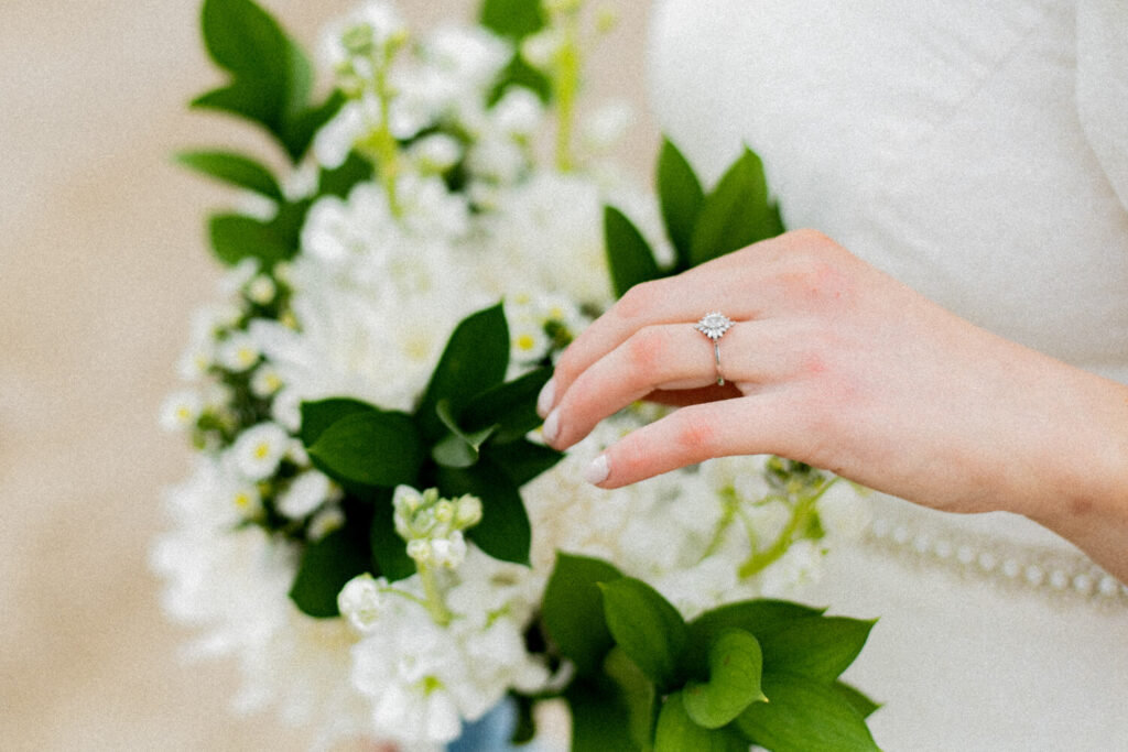 Hand touching a bouquet with the ring in focus