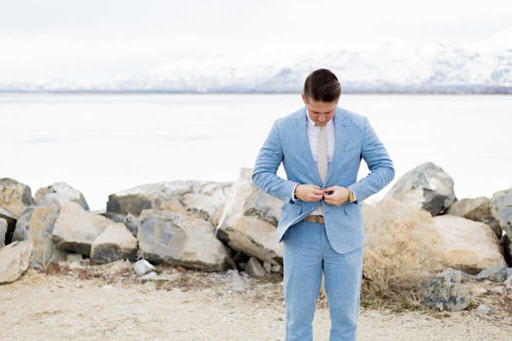 Groom looking down while buttoning his suit jacket