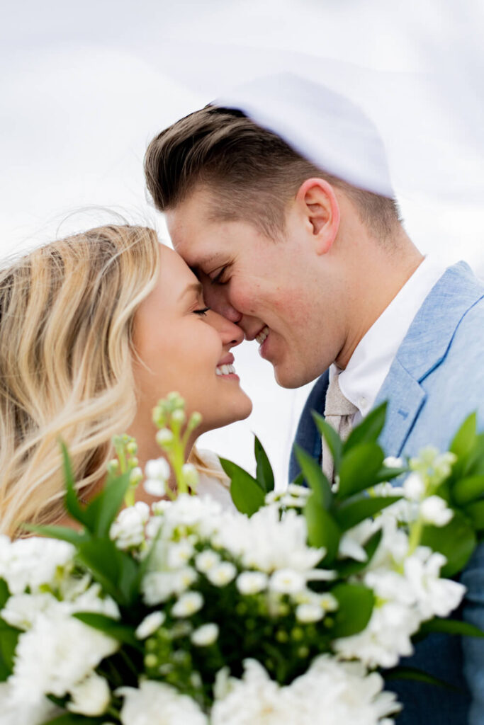 Bride and groom almost kissing with flowers by their faces
