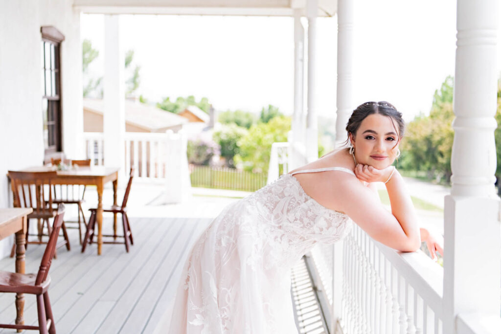 Bride leaning against the railing on a porch