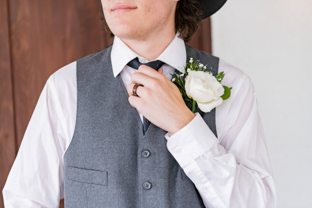 Closeup of a groom adjusting his tie