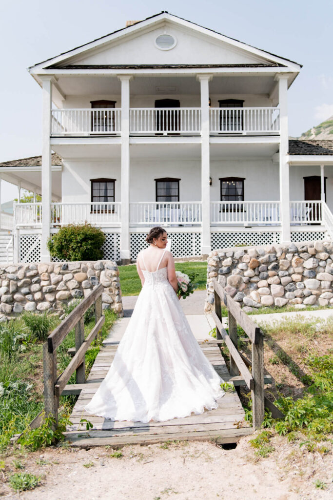 Bride standing on a bridge with a house in the background