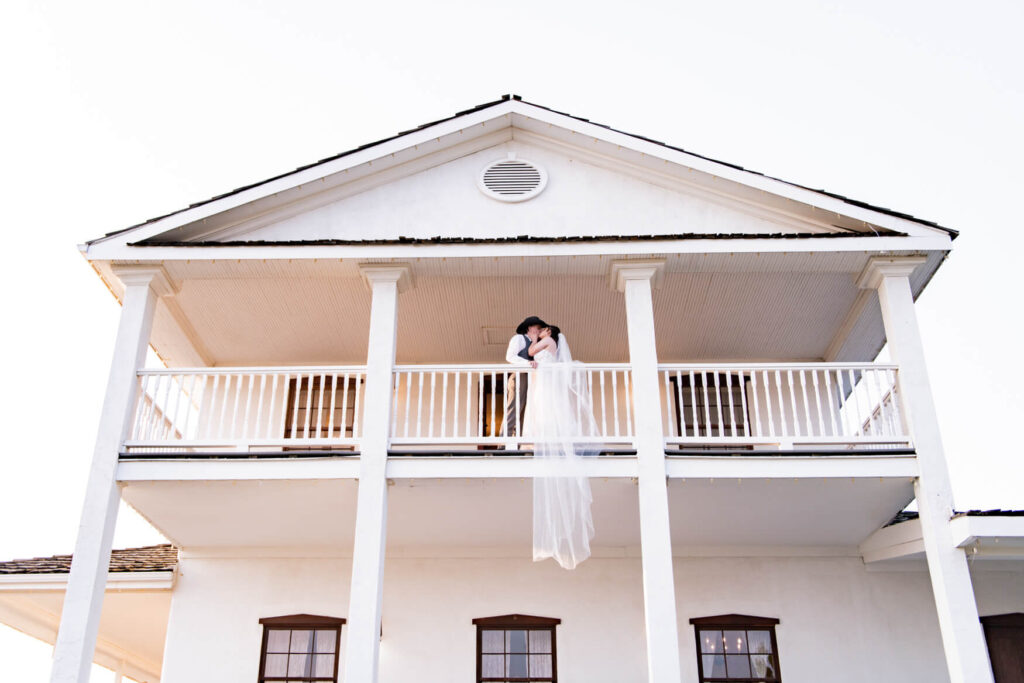 Bride and groom kissing on a balcony of a house