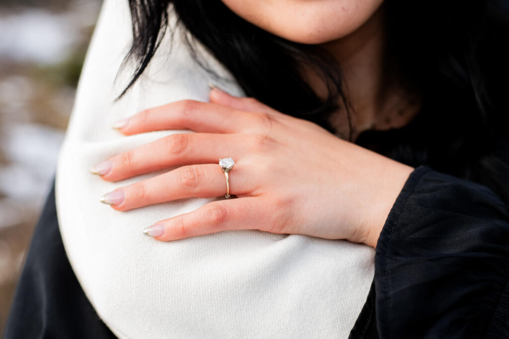Woman's hand on an arm with a closeup of an engagement ring.