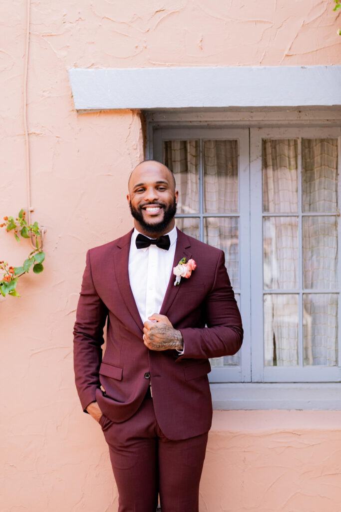 Groom standing and holding his jacket smiling at the camera.
