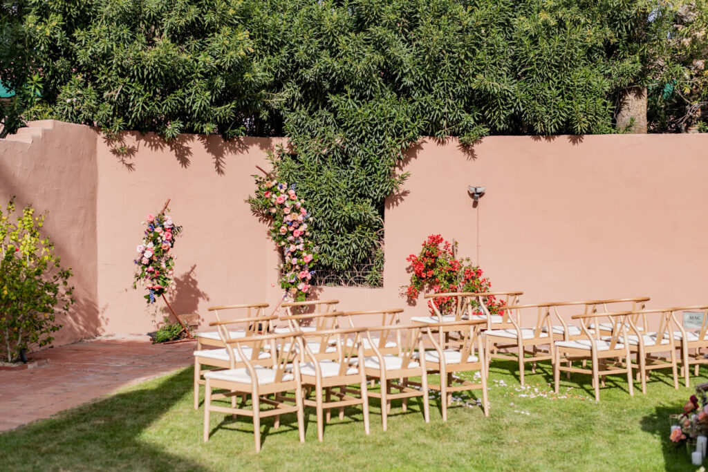 View of the ceremony space with a flower arch at the front and empty chairs.