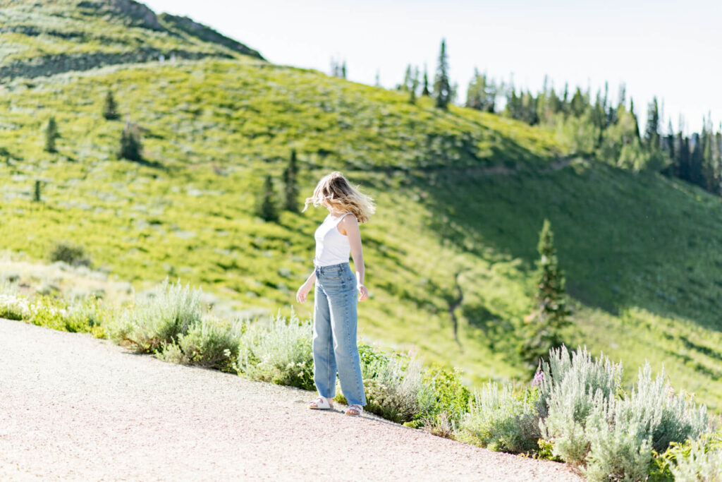 Girl flipping her hair over her shoulder with green hills behind her