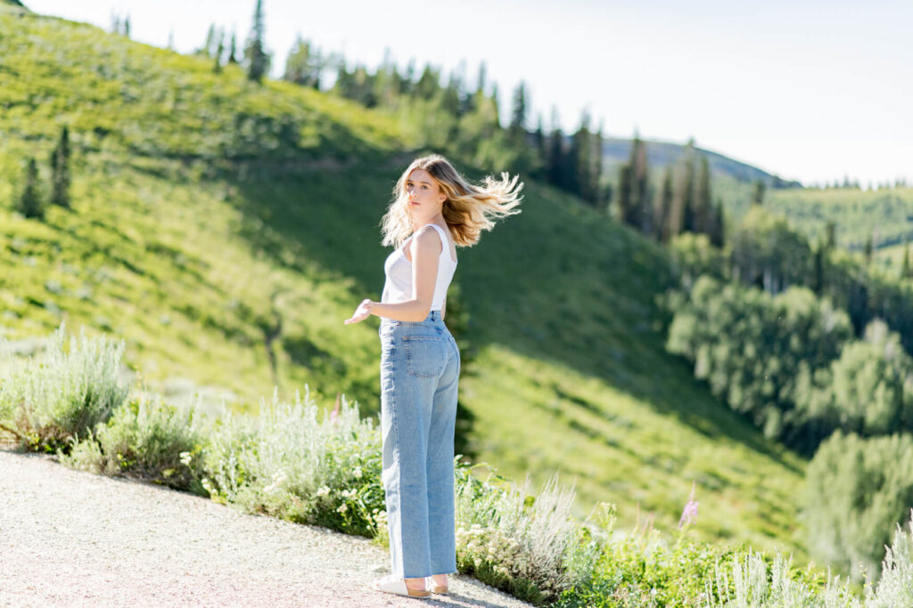 Girl flipping her hair over her shoulder with green hills behind her