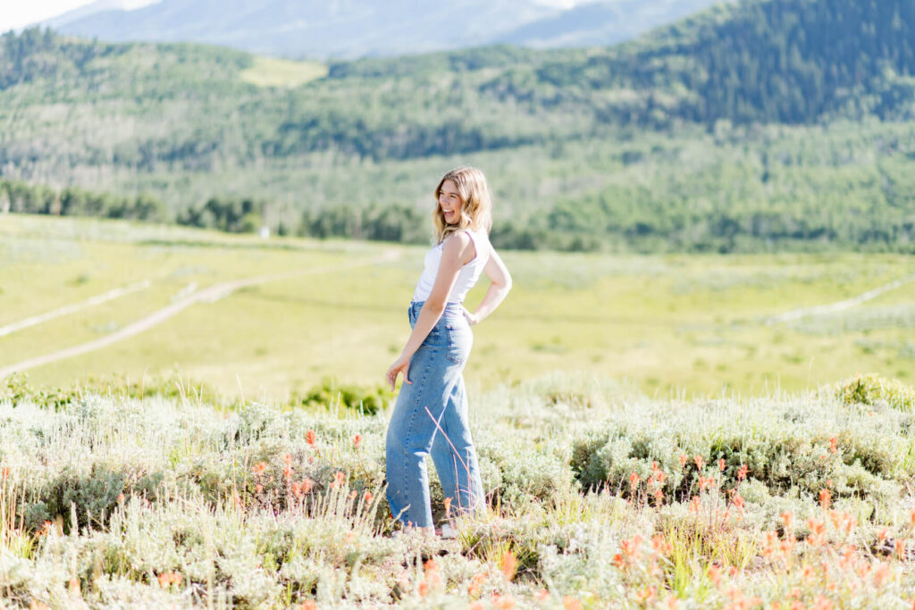 Girl in a meadow with hands on her hips looking over her shoulder to the camera