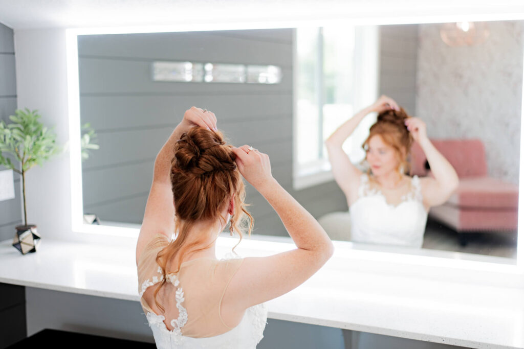 Bride adjusting her hair in front of a long mirror