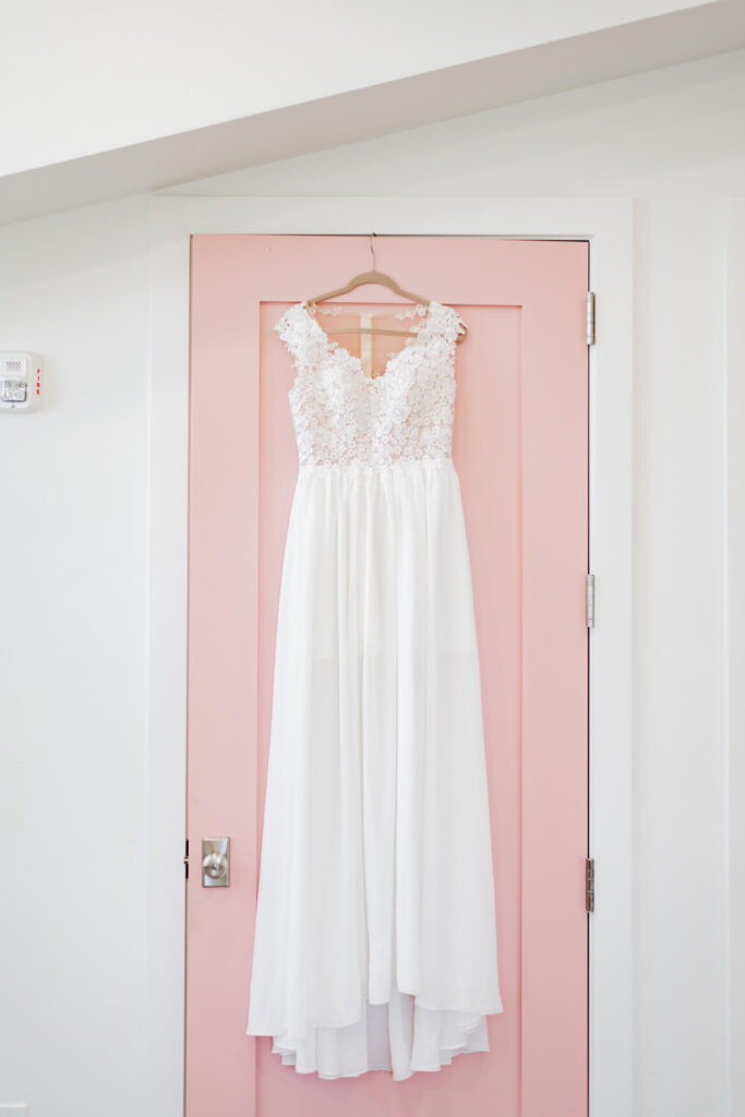 Wedding dress hanging on a pink door