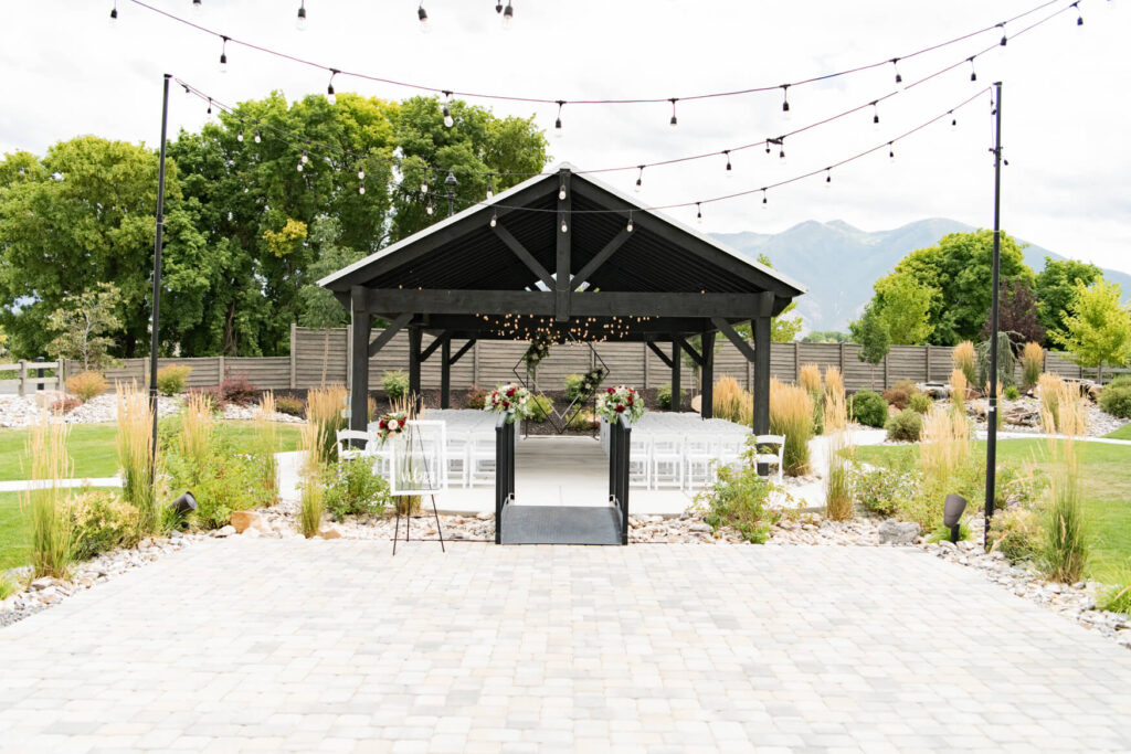 View of the pergola with chairs and an arch set up for a ceremony.