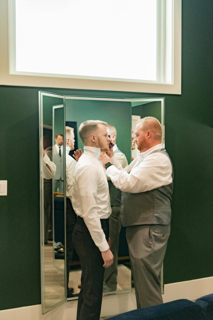 Groomsman helping groom with his tie