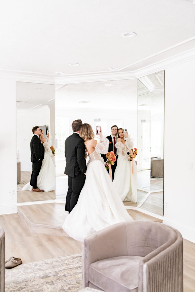 Bride and groom taking a selfie in a big mirror