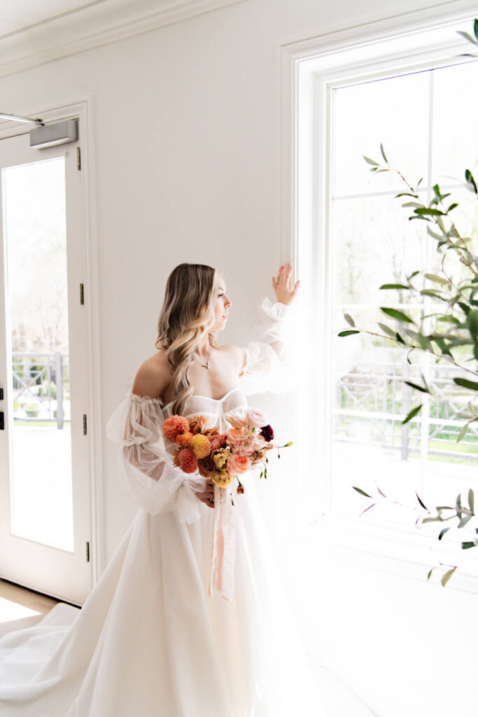 Bride standing in front of a big window and looking outside
