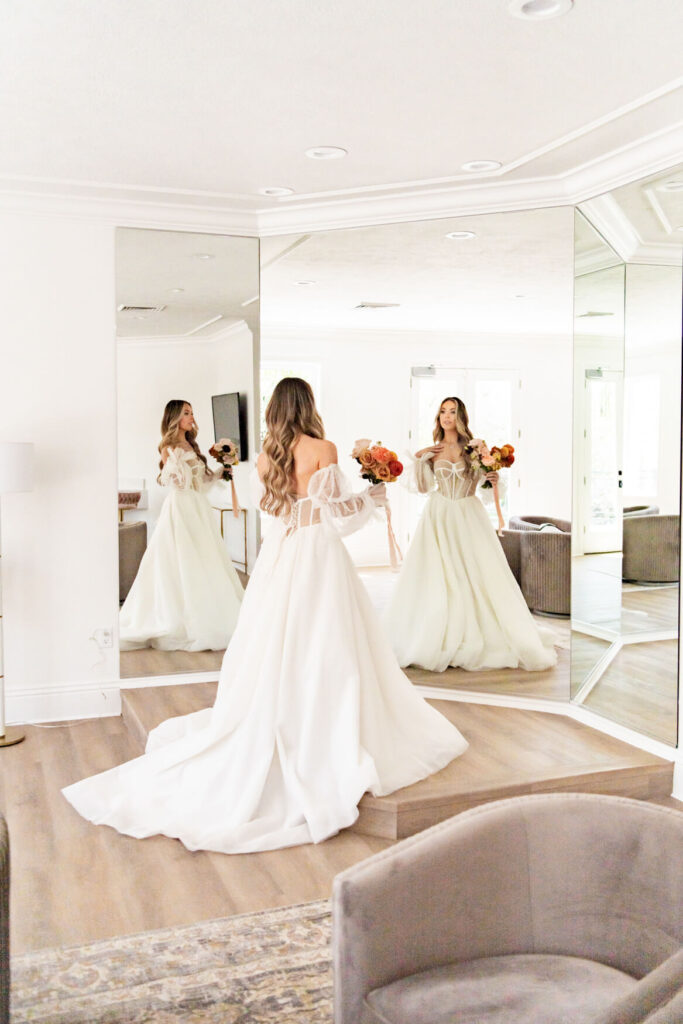 Bride standing and looking at herself in a huge mirror