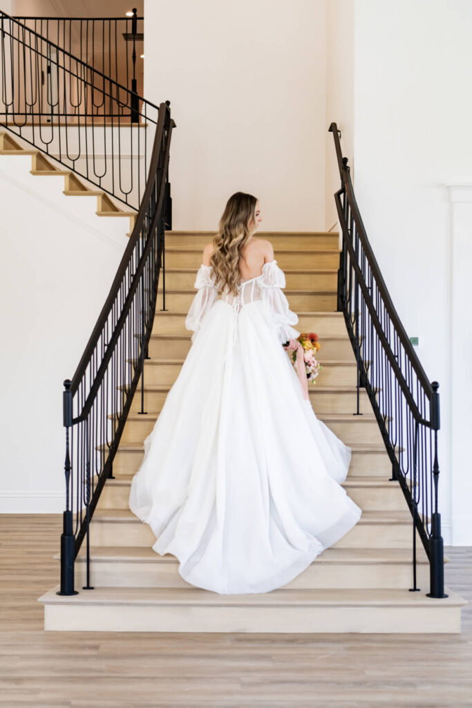 Bride standing on the stairs with her dress flowing behind her