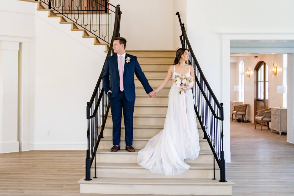 Bride and groom standing on the stairs, looking opposite directions, and holding hands
