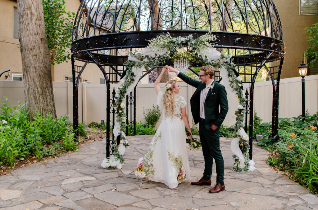 Groom spinning bride outside underneath a pergola